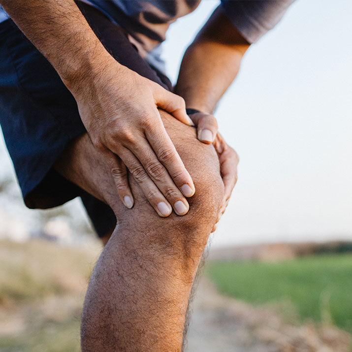 HOCHENERGIE-INDUKTIONSTHERAPIE | ORTHO AKTIV Weibern Abgebildet wird eine Mann mit Knieschmerzen. Dieser greift sich an sein Knie um den Schmerz zu verarbeiten.